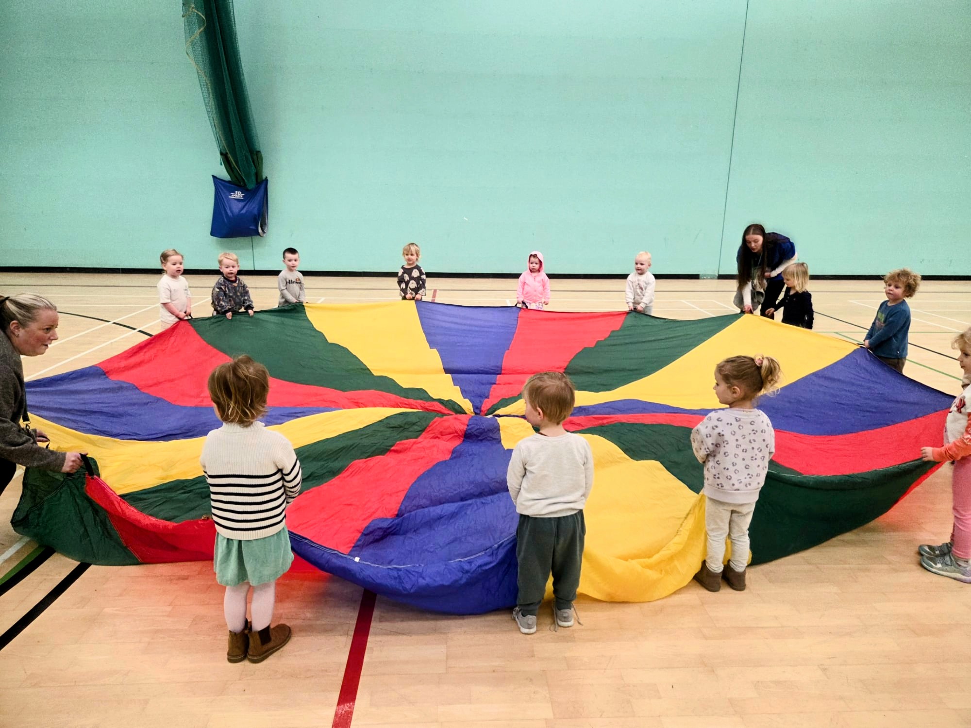 Children enjoying a parachute activity at Brambles Nursery